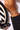 Hand wearing a tennis bracelet with a striped white and black plate on a table, featuring 'Oriki Line' branding.