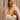 Smiling bride wearing a white ruched gown, diamond V-shaped necklace, Adéọlá pavé stud earrings, and a solitaire engagement ring, with a soft tulle veil draped over her shoulders.