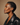 Woman wearing a black leather jacket against a beige background. Profile of a woman with short hair wearing a black leather jacket against a beige background iin DOLA ÀMÌ Single Link Petite Stud Earrings in 18ct white gold worn on ear, African luxury fine jewellery gold stud earrings London, as featured in Vogue
