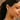 Close-up of a woman wearing diamond earrings and a tennis necklace against a neutral background